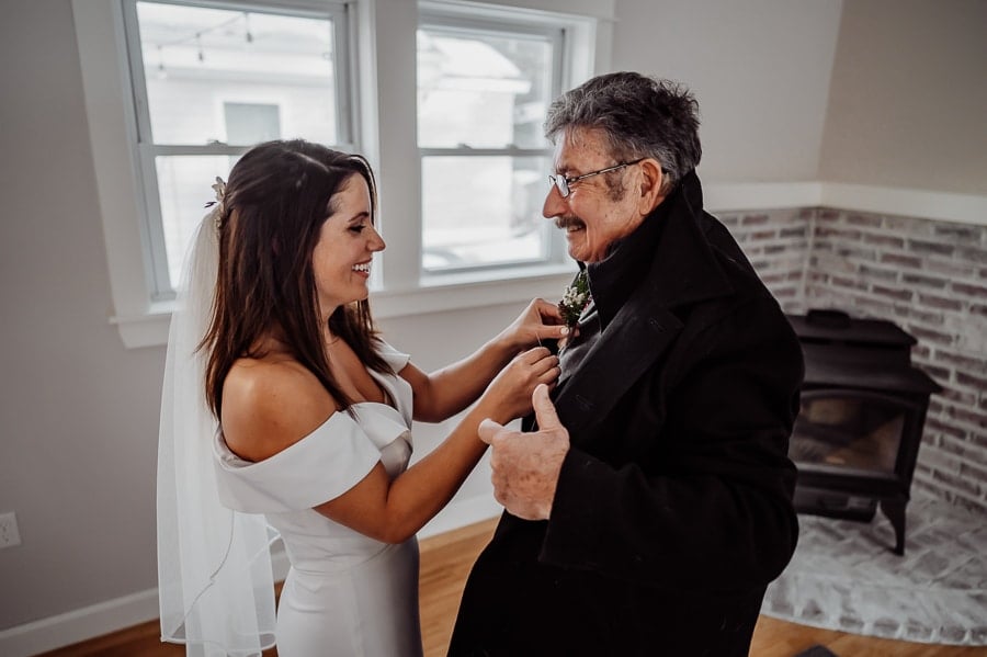 Bride pinning a boutonniere on her fathers jacket