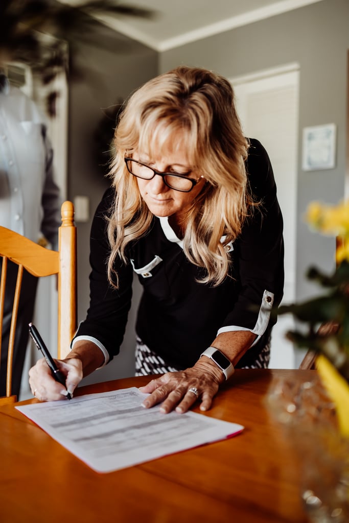 A woman signing a document at a table while concentrating