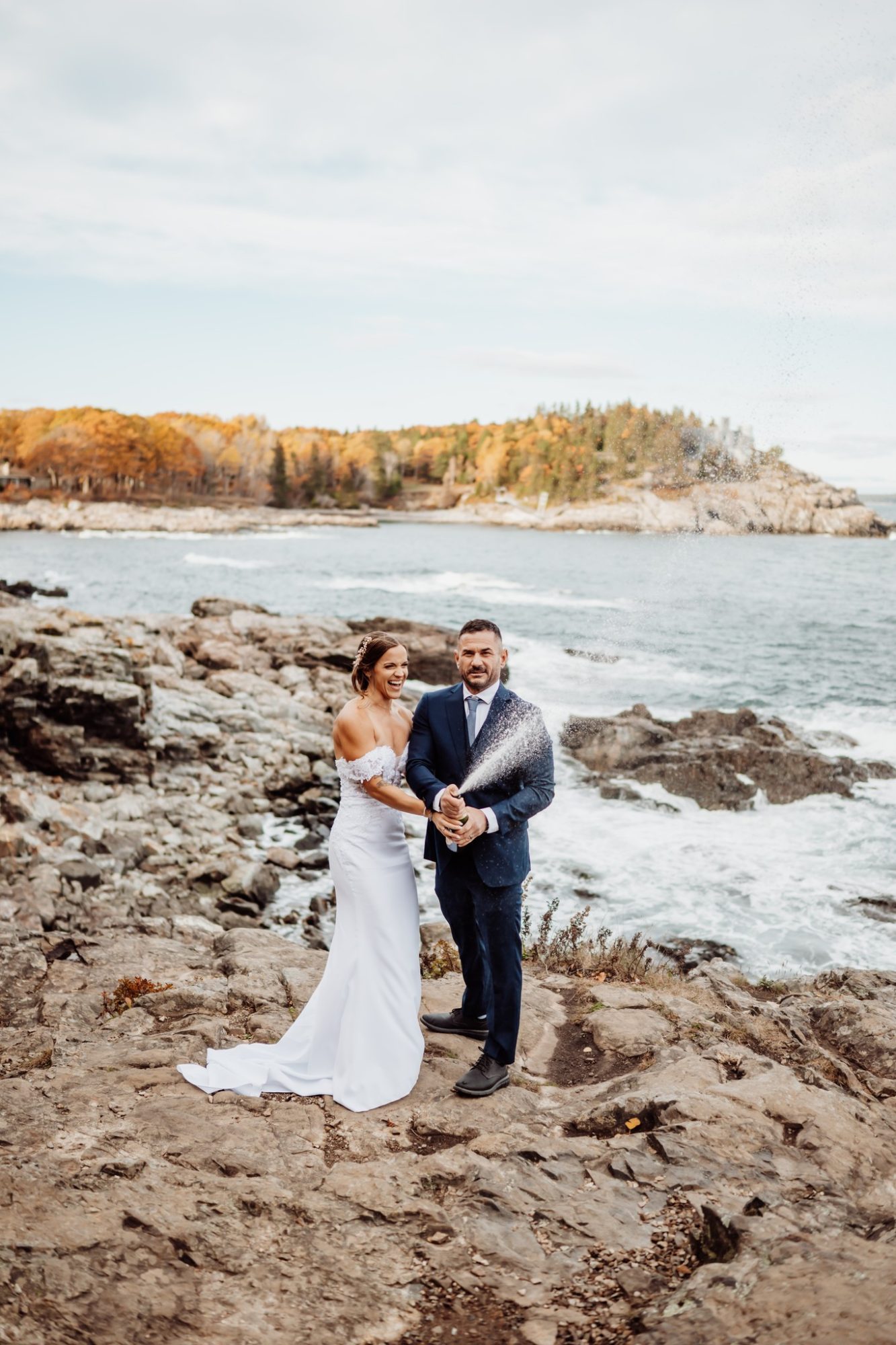Bride and groom standing on rugged coastal cliffs during their Schooner Head Overlook elopement in Acadia National Park.