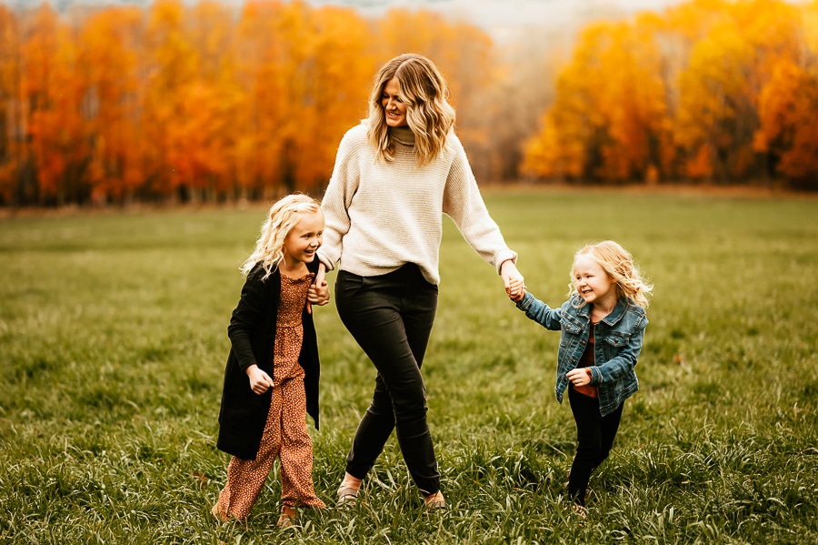 Mother and children walking in field against fall trees