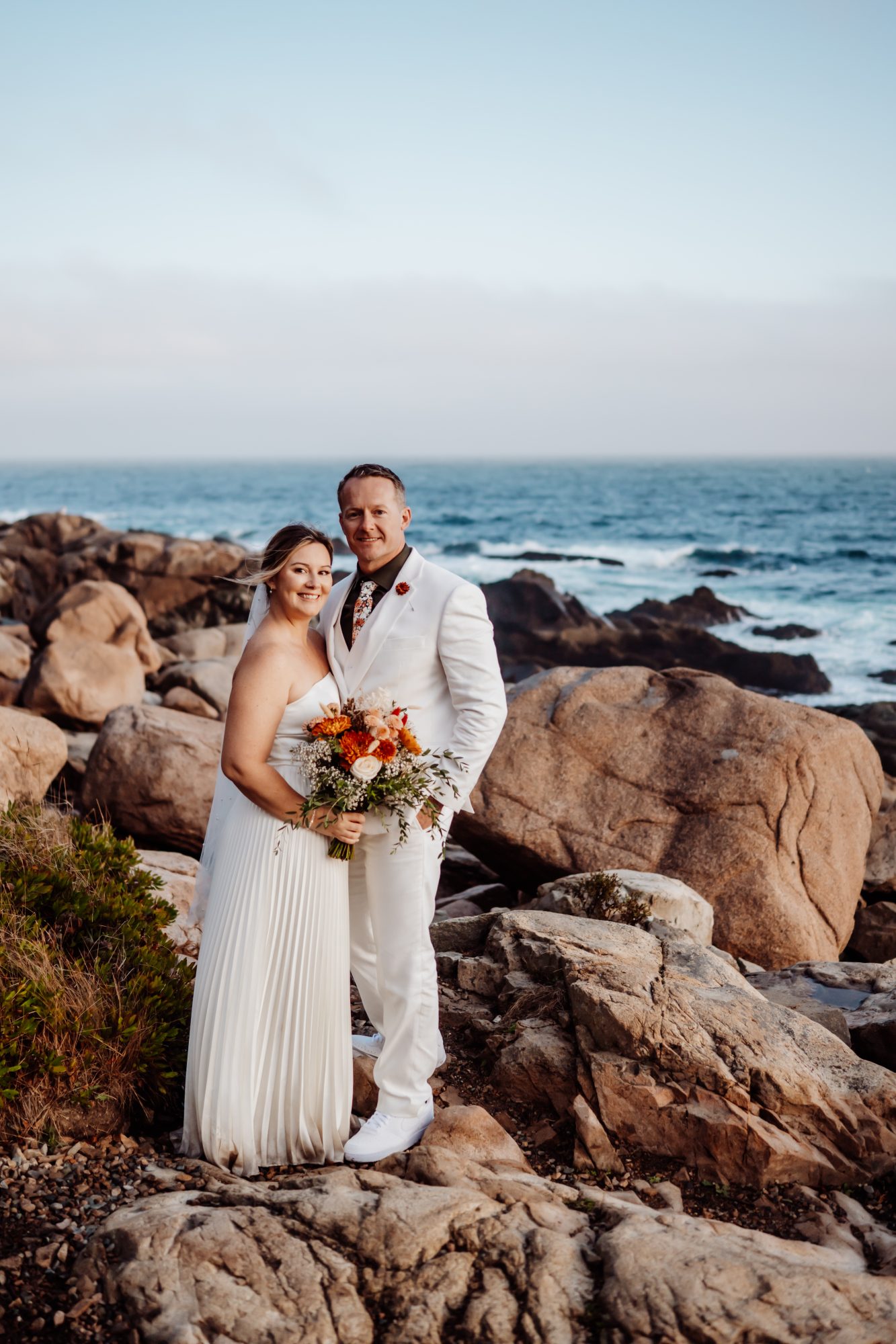 Bride and groom on rocky Atlantic coastline during Thunder Hole elopement in Acadia.