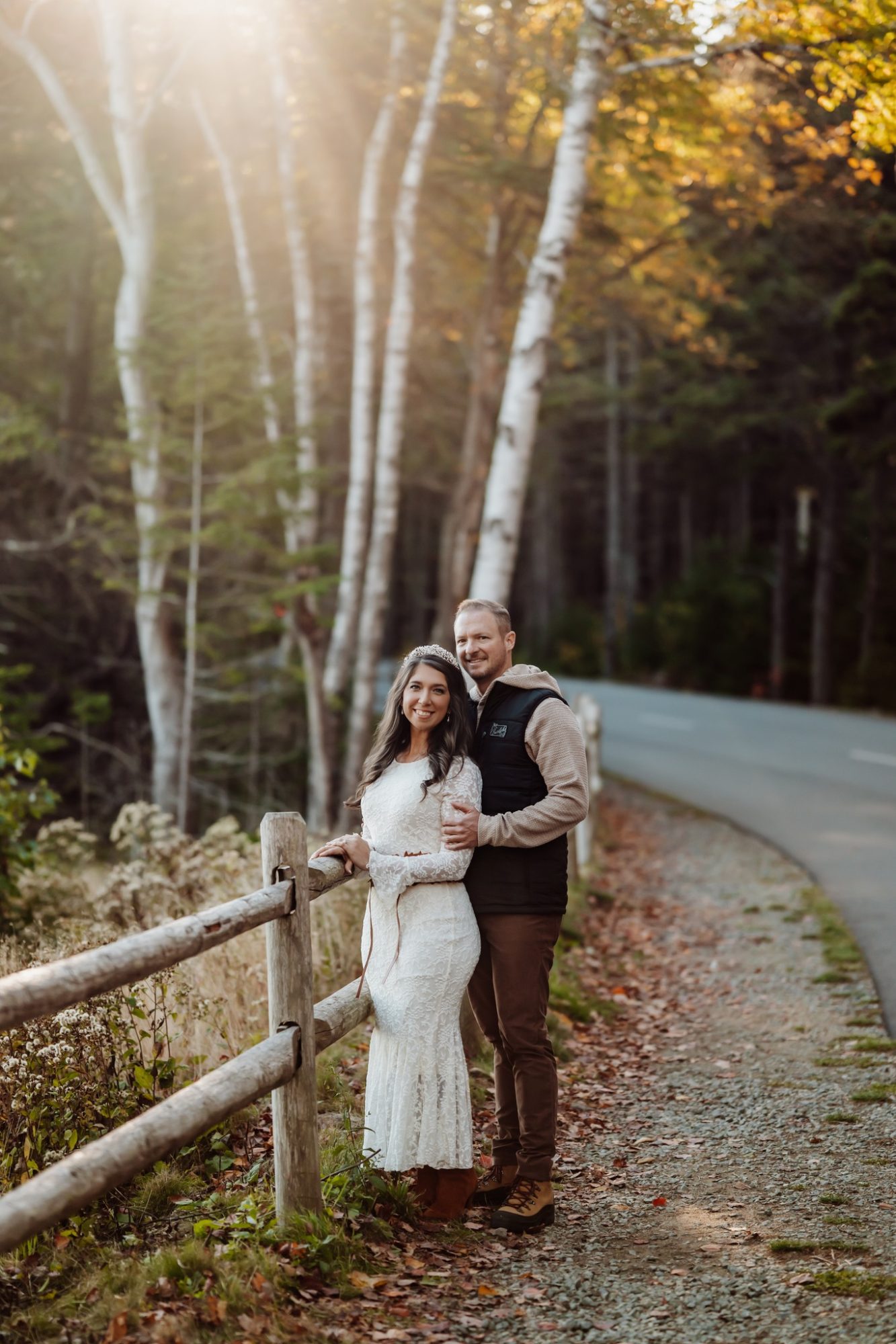 Bride and groom walking along wooded road during autumn elopement in Acadia.