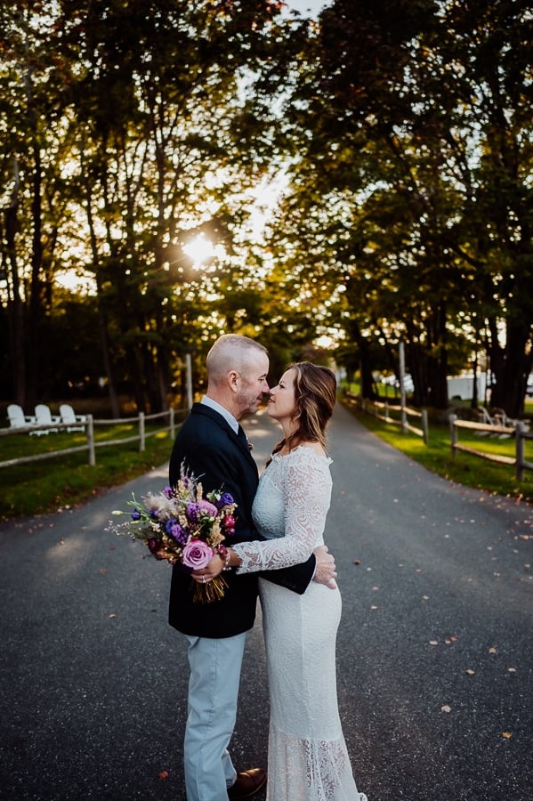 Bride and groom facing nose to nose in front of trees at Bar Harbor inn