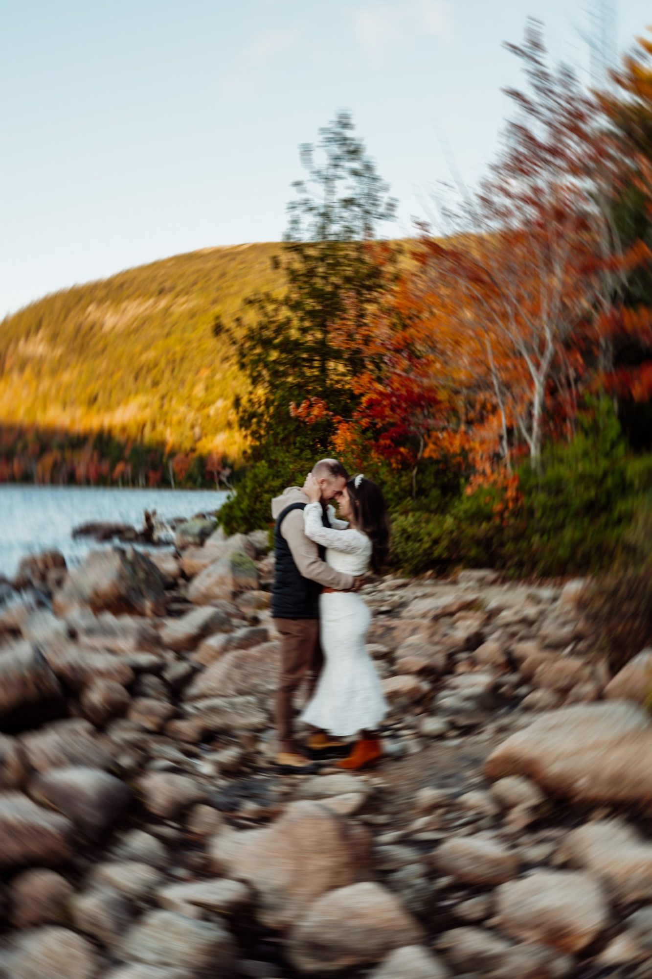 Romantic lakeside embrace with golden fall mountain reflections in Acadia.