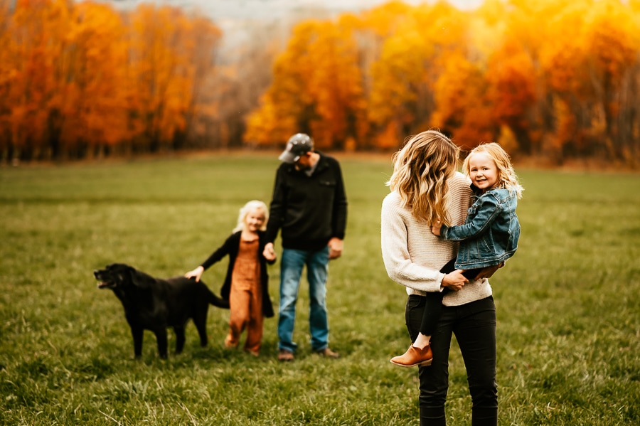 Family of 4 and black dog in field
