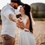 Couple facing each other and holding hands with the hands stretched out in focus