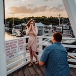 woman covering face in excitement with man proposing on one knee