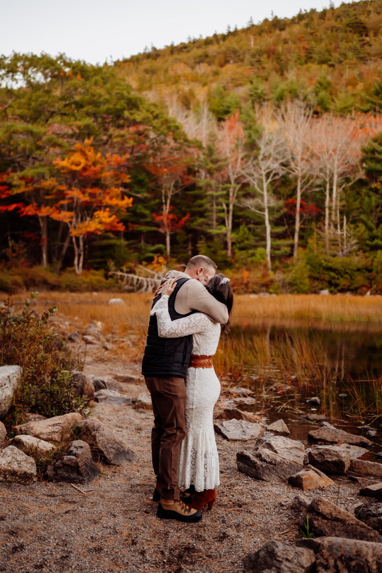 Couple embracing beside golden fall foliage during elopement in Acadia National Park.