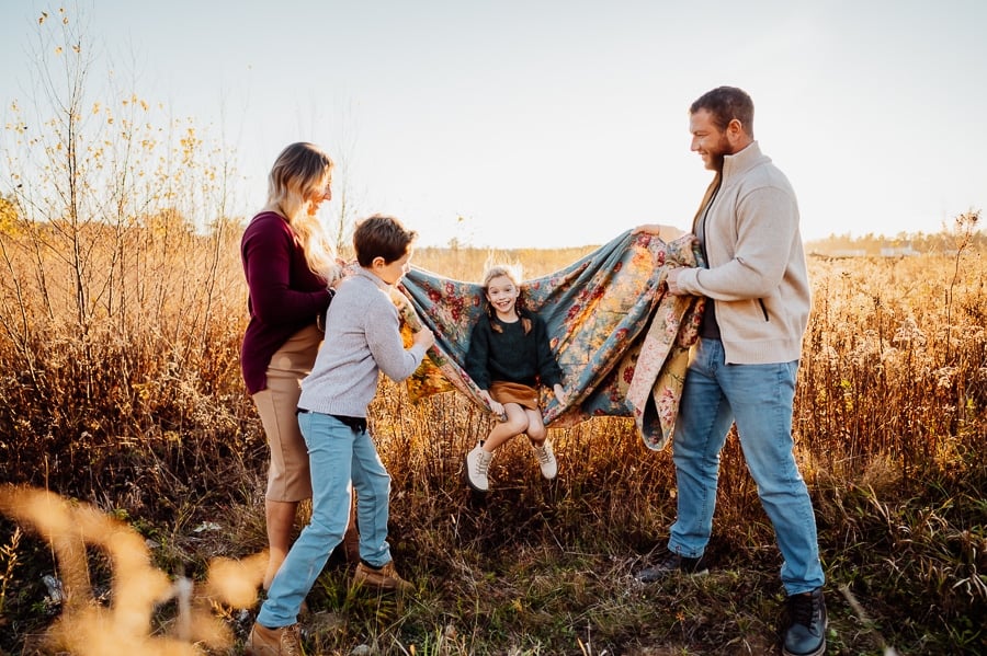 Family swinging little girl on blanket