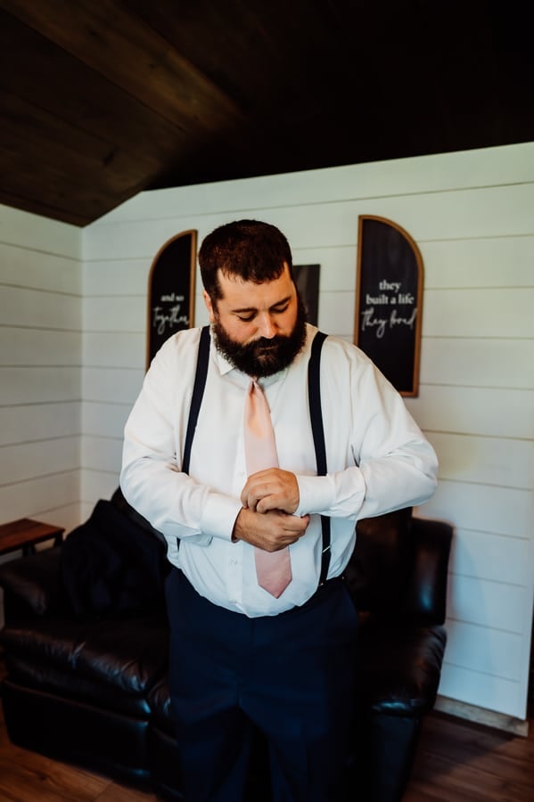 groom fixing cuff links before wedding