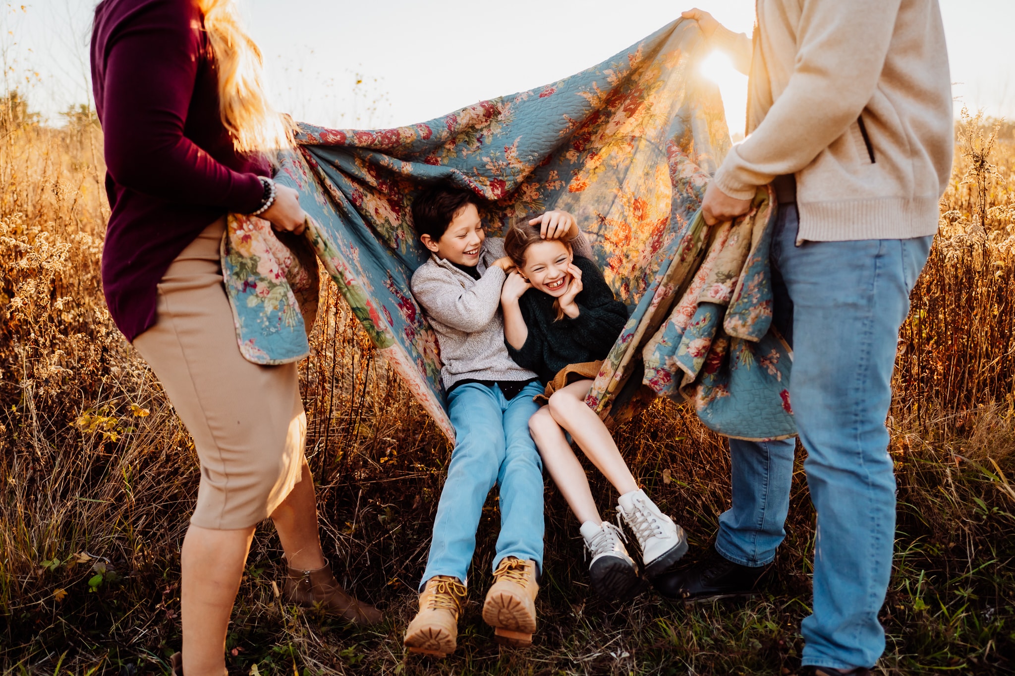 Siblings swinging on blanket together and laughing