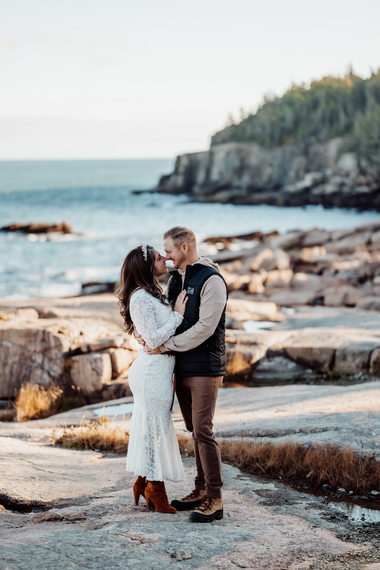 Bride and groom sharing a kiss on rocky Acadia coastline during autumn elopement.