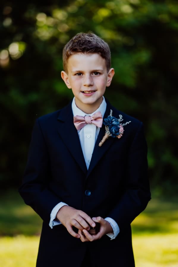 ring bearer wearing a tux holding ring box