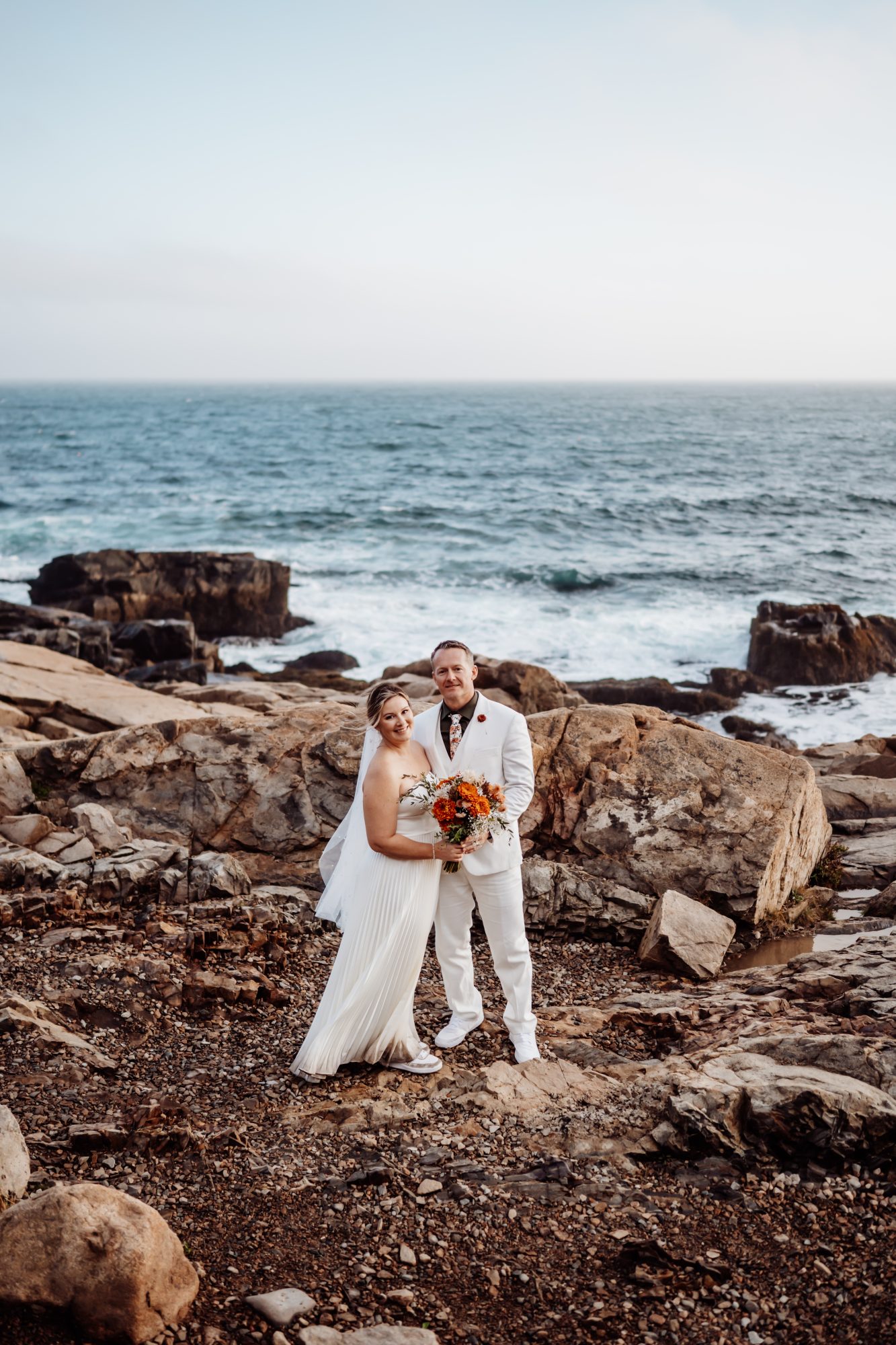 Newly married couple on rugged coastal rocks at Thunder Hole elopement.