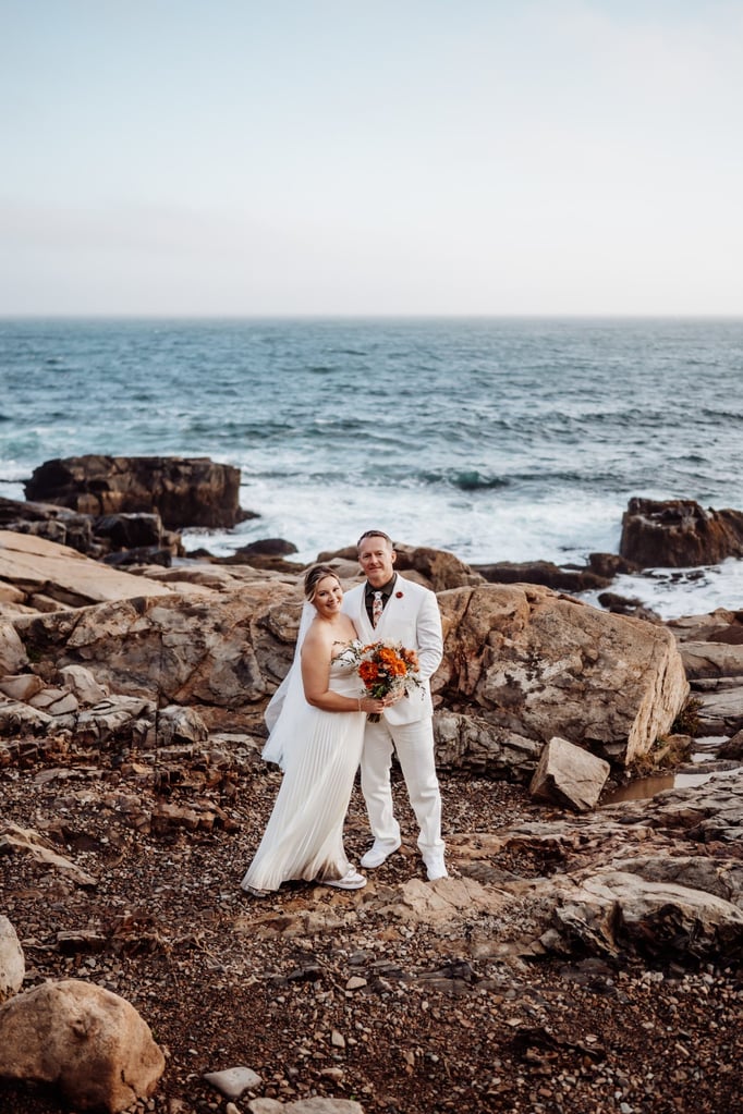 Newly married couple on rugged coastal rocks at Thunder Hole elopement.