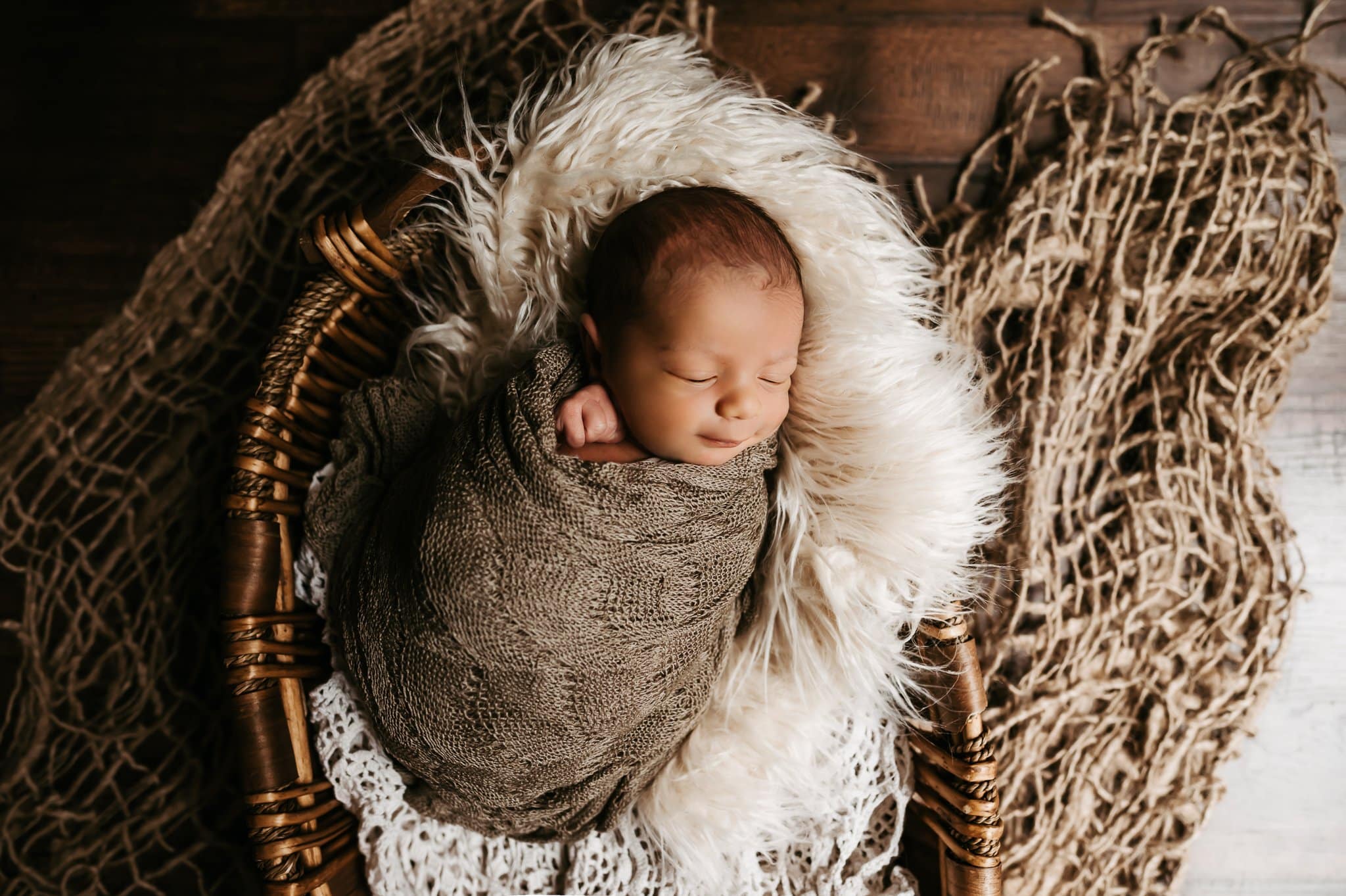 Newborn baby wrapped in scarf sitting on her and basket