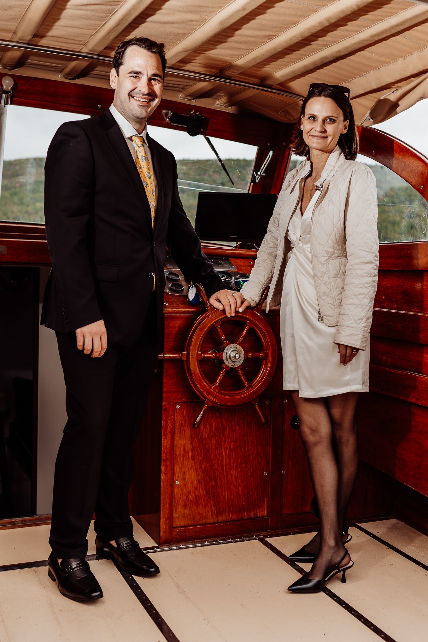 Bride and groom both standing at the wheel of the boat