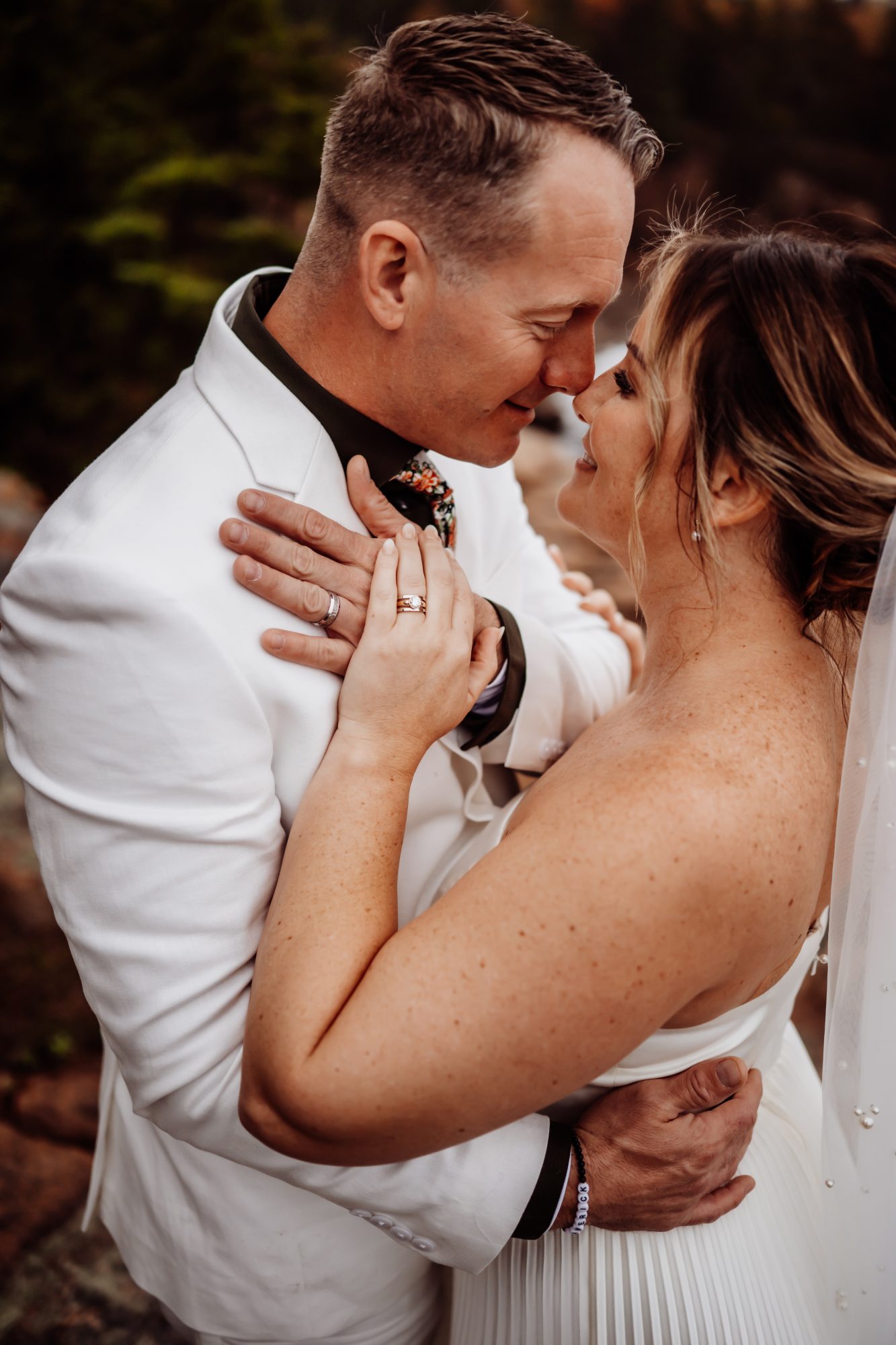 Intimate portrait of bride and groom embracing along the Thunder Hole coastline in Acadia.