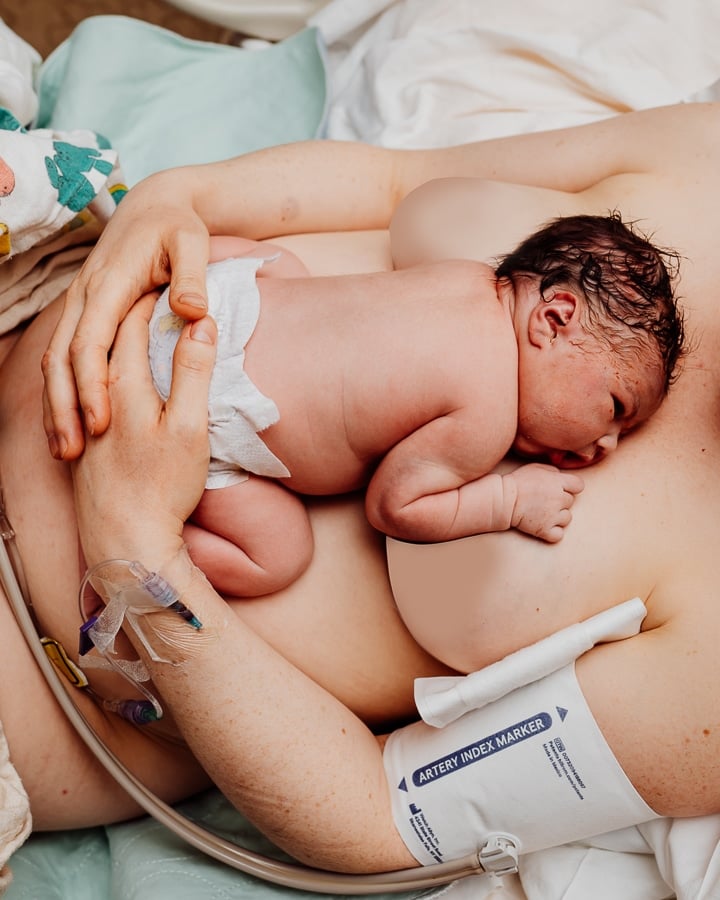 Newborn baby laying flat on mothers chest