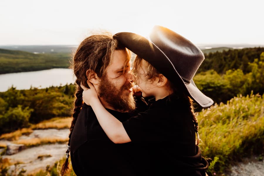 Father and son hugging in cowboy hat in acadia