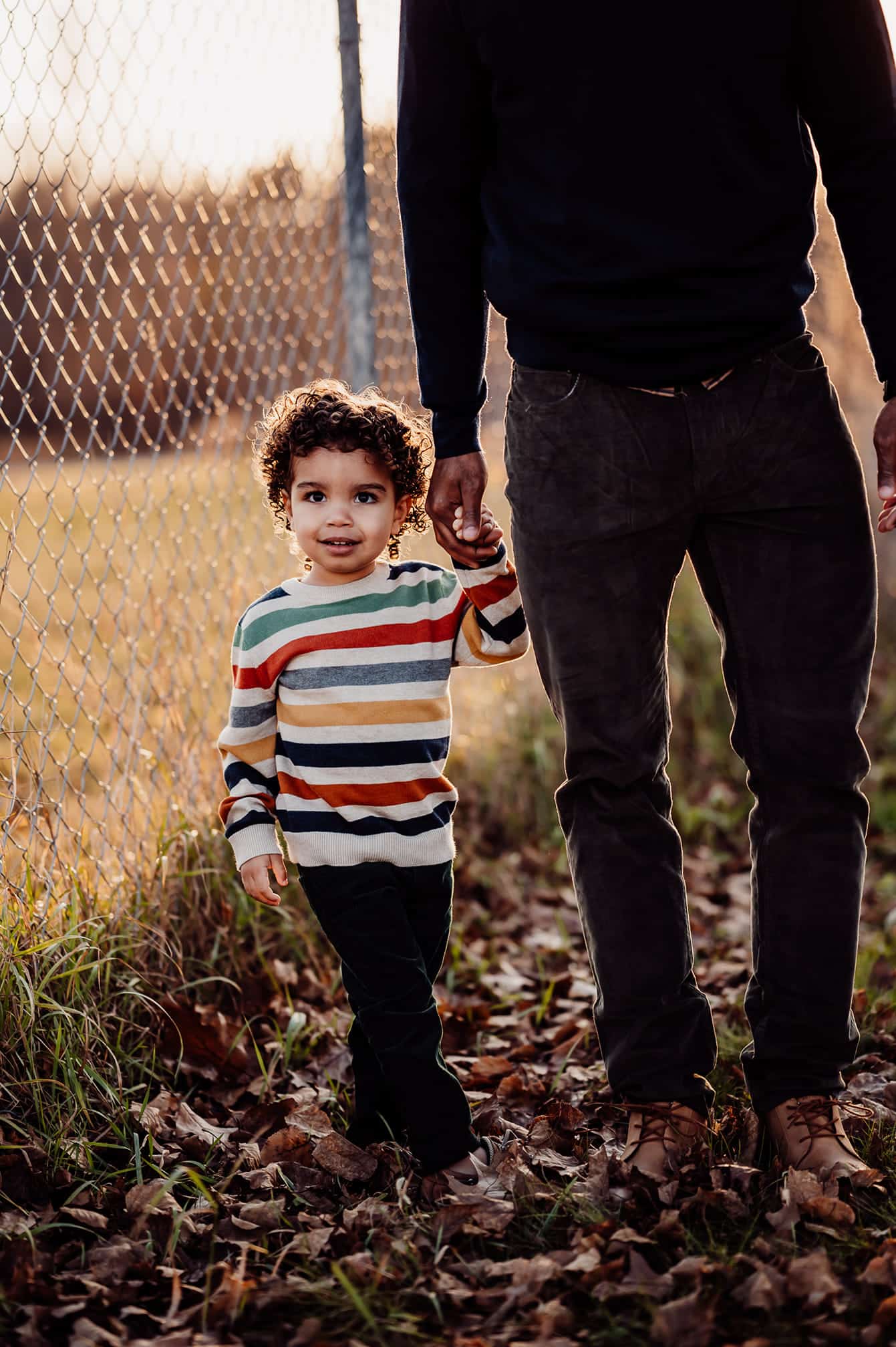 Little boy wearing a striped sweater holding hands with his dad