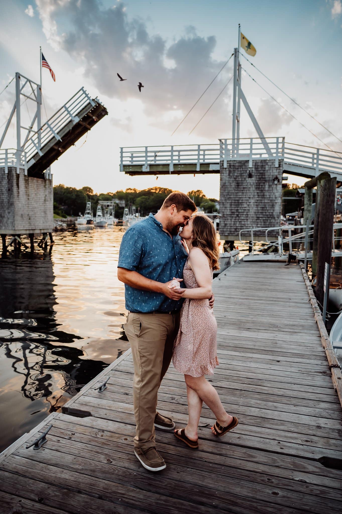 Engaged couple standing close in front of Perkins Cove drawbridge