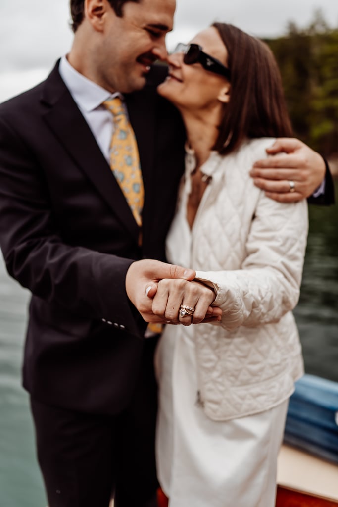 Bride and groom embracing with the brides hand and ring in focus