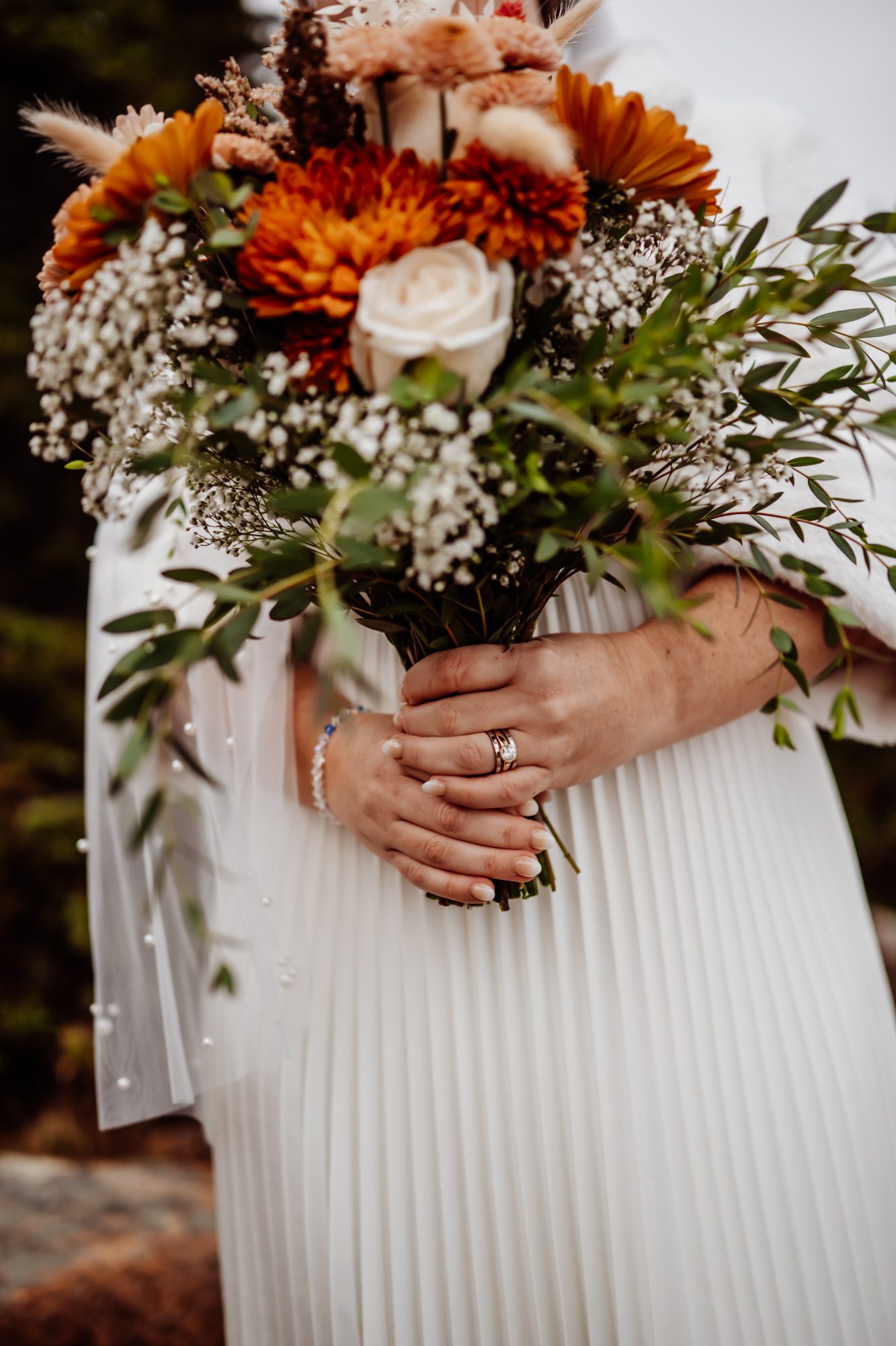Bride holding autumn wedding bouquet during Thunder Hole elopement in Acadia National Park.
