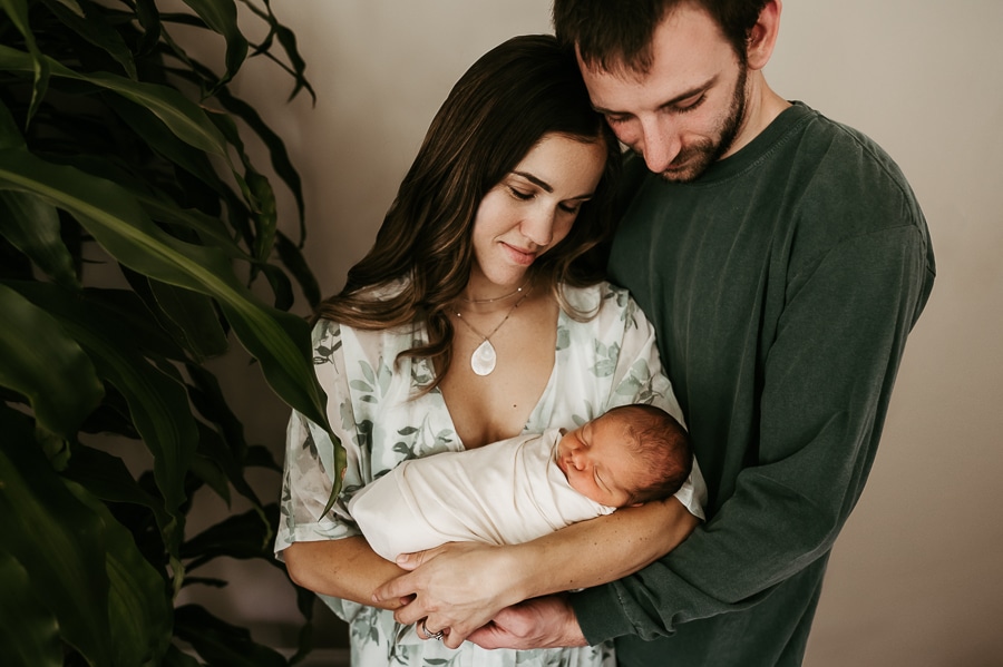 Mother and father holding newborn baby together