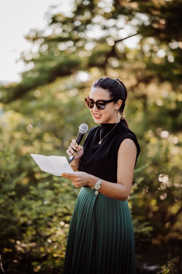 Woman wearing green dress holding microphone and wearing sunsglasses