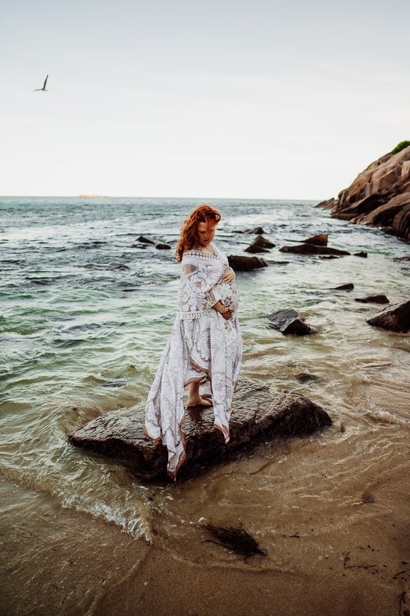 Woman on rock in ocean at sand beach