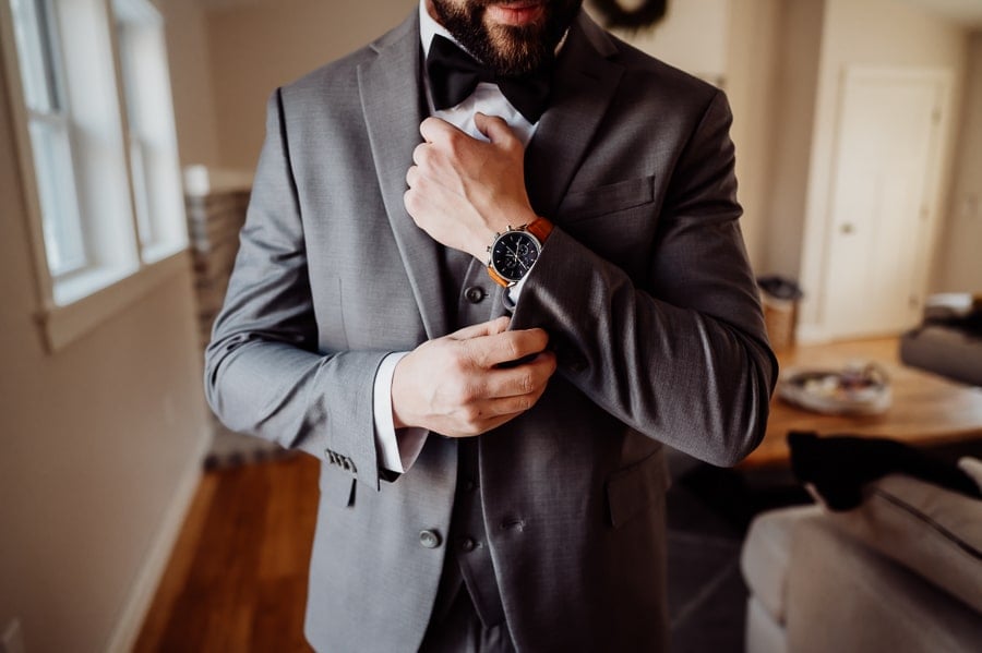 Groom fixing cuff links with a watch on his wrist