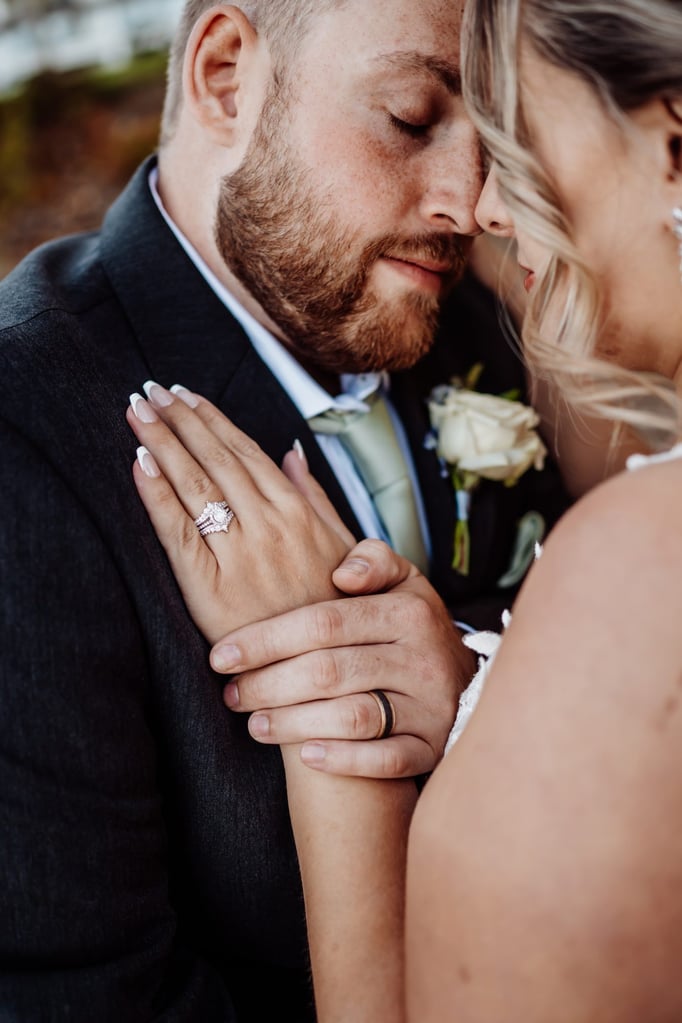 Close-up of the groom holding the bride’s hand, showing her diamond wedding ring as they share a quiet, emotional moment after their Acadia National Park ceremony.