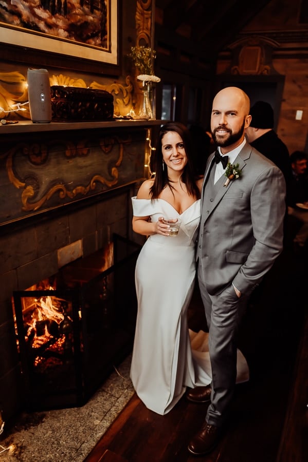 Bride and groom standing together next to fireplace