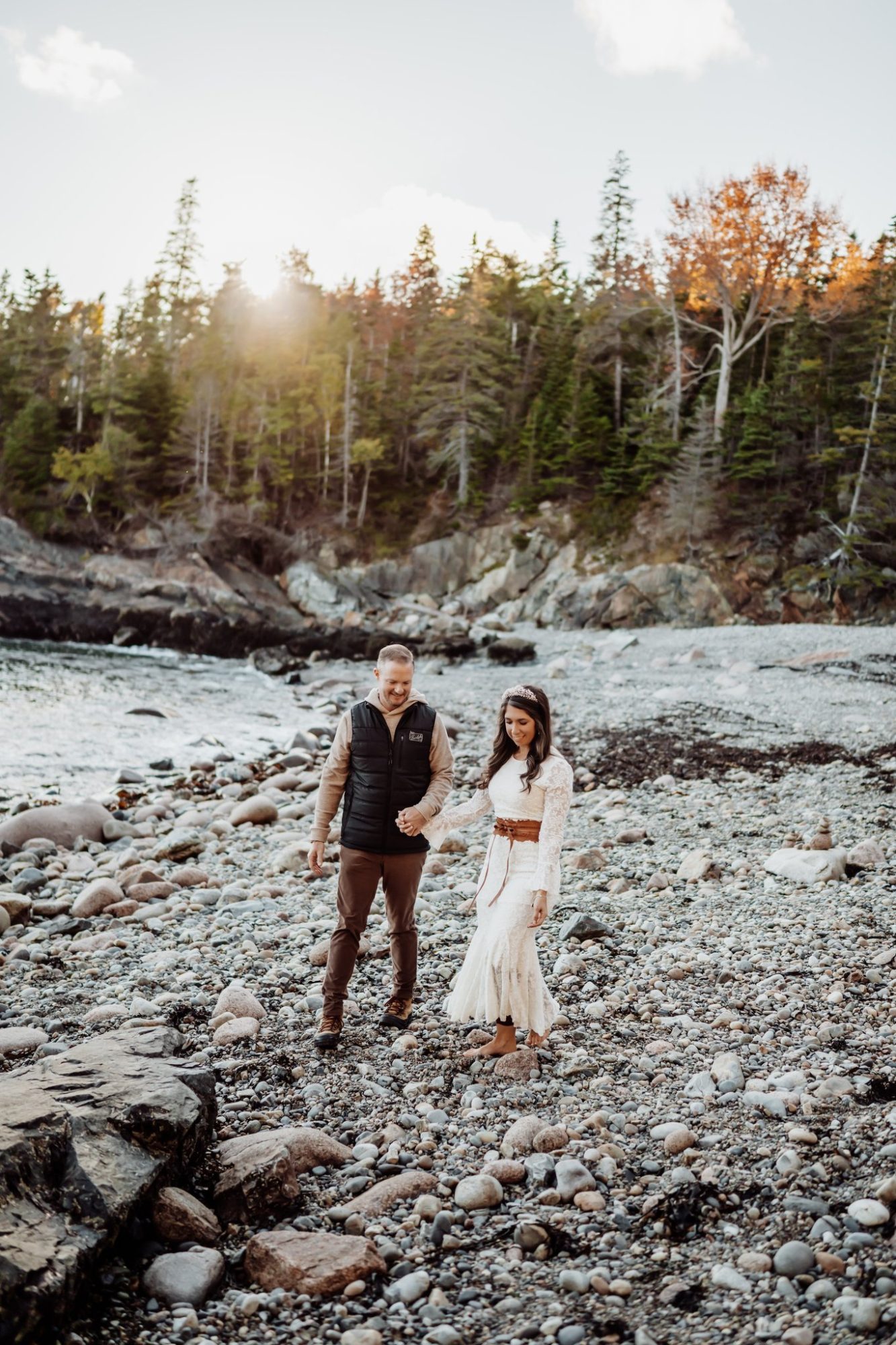 Couple standing along rocky coastline during autumn elopement in Acadia National Park