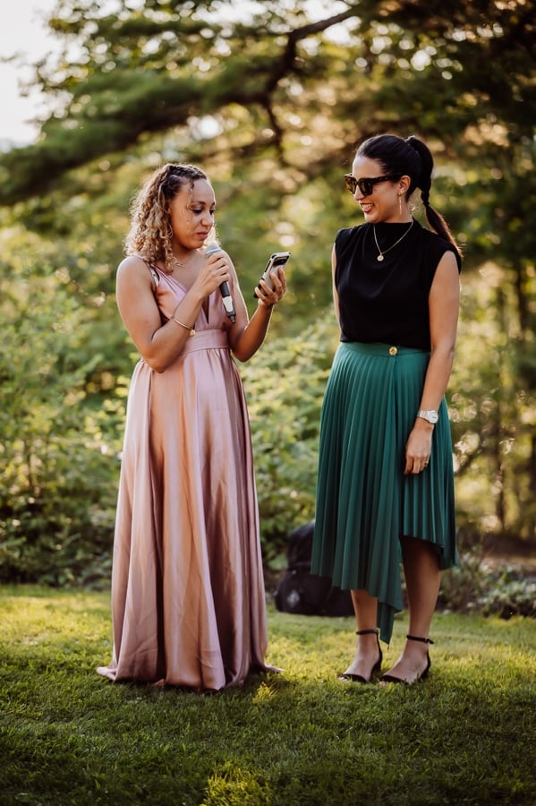 Bridesmaid giving speech wearing a pink dress holding a microphone outside