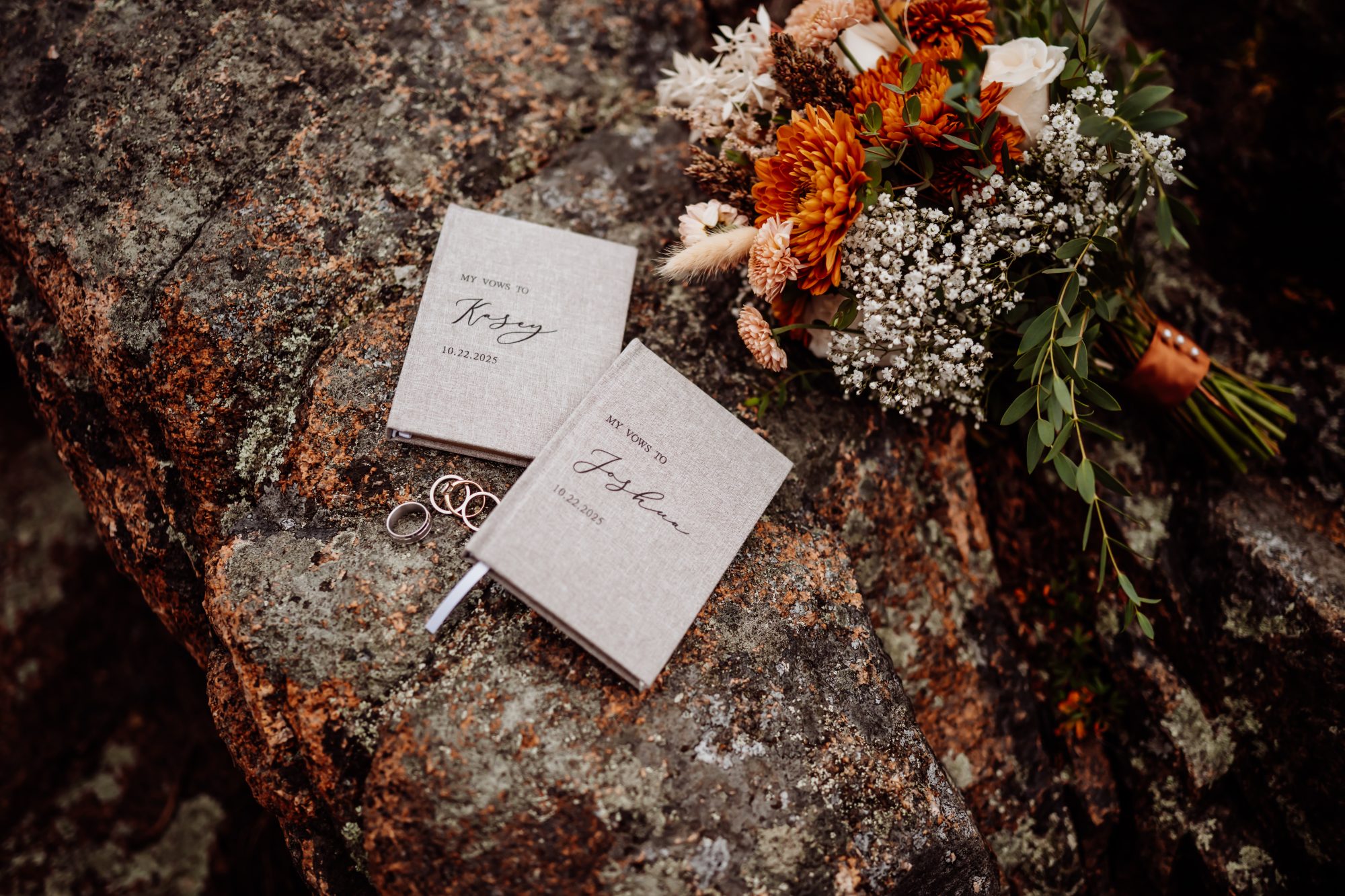 Elopement vow books and bouquet arranged on granite rocks at Thunder Hole in Acadia.