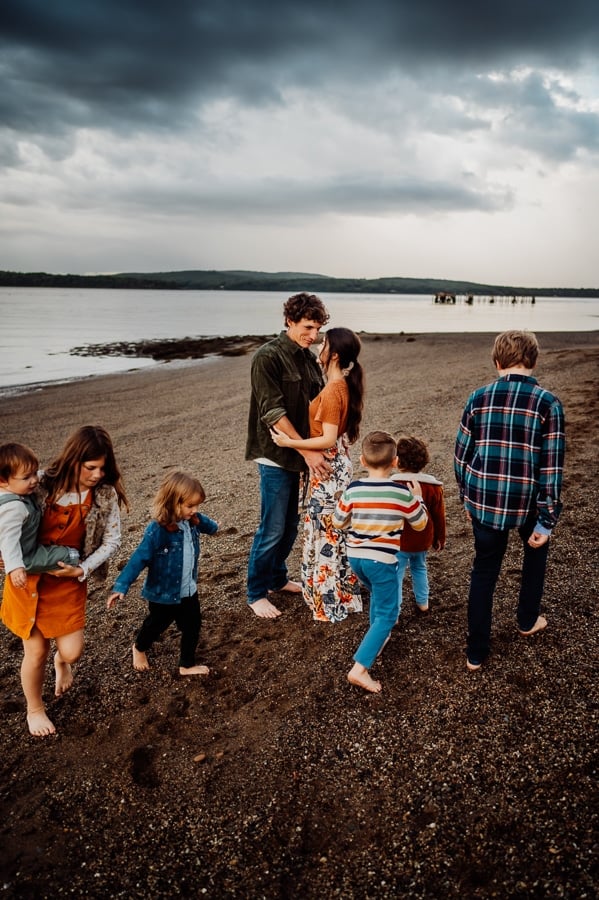 Couple facing each other with lots of children running around parents