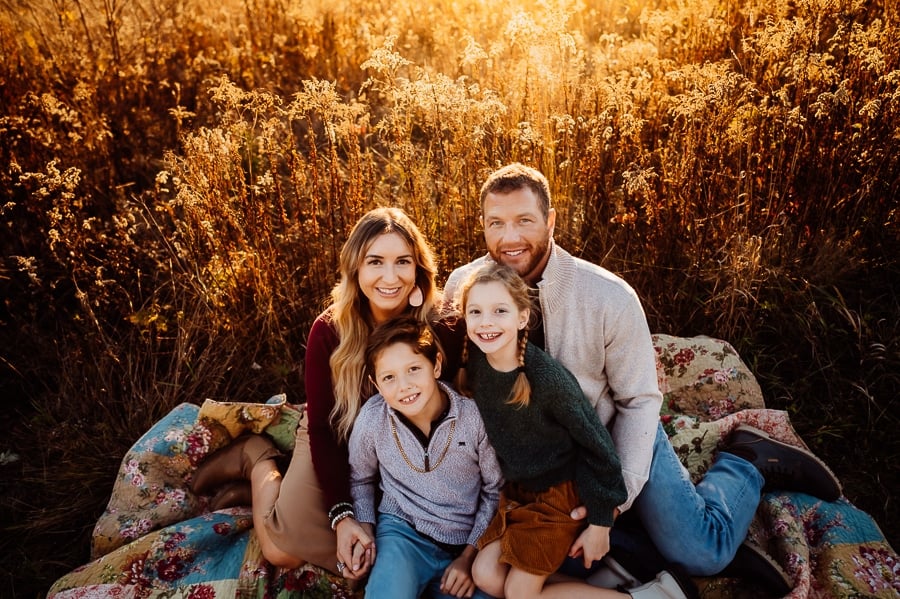Family sitting on quilt together at sunset