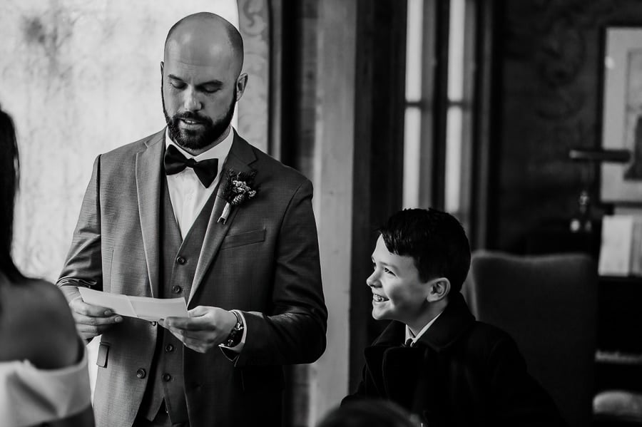 Groom saying vows at wedding ceremony with ring bearer smiling