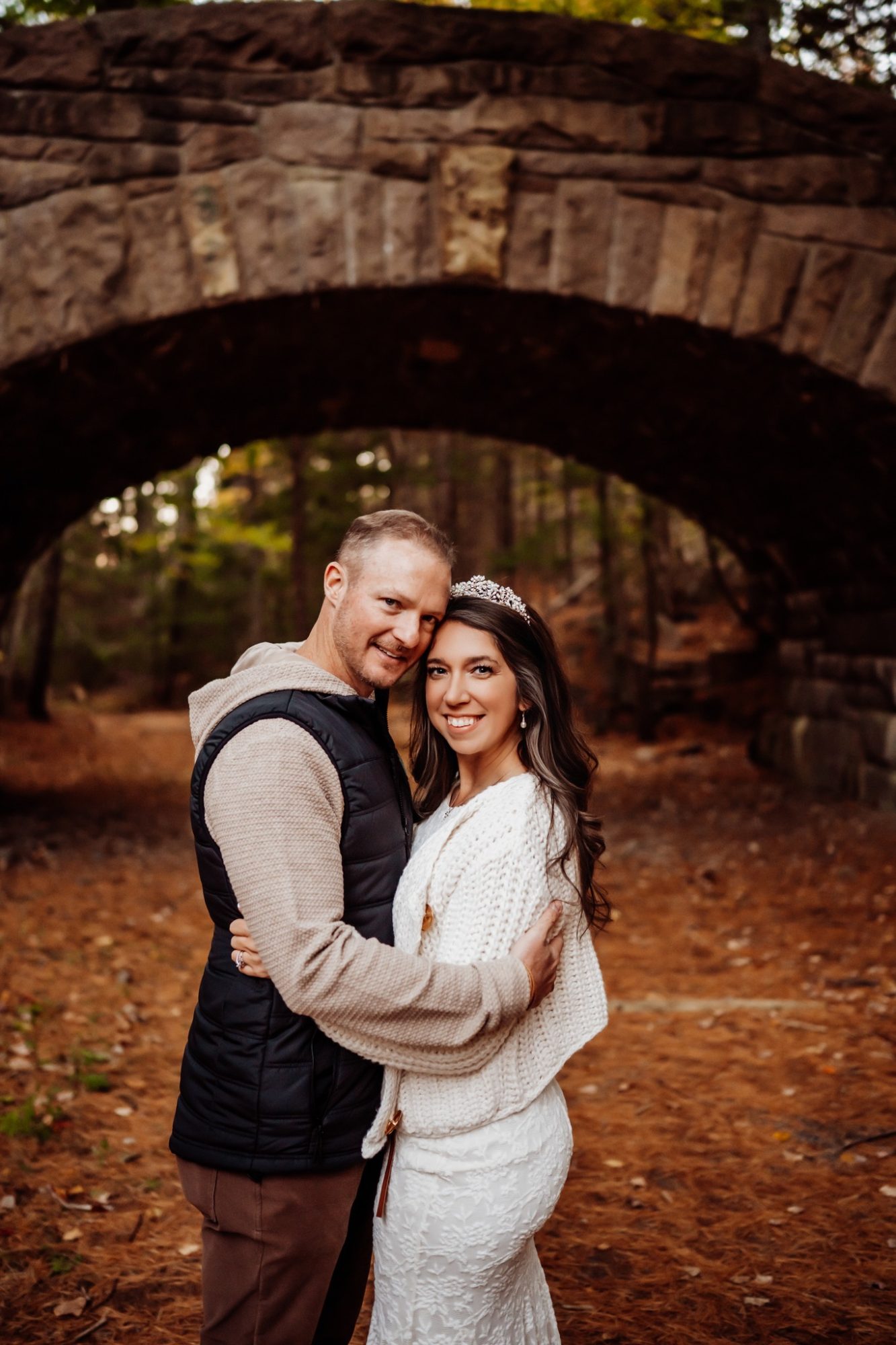 Bride and groom under historic stone bridge during fall elopement in Acadia.
