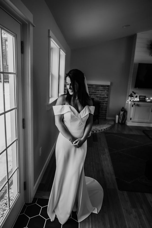Bride standing next to window in black and white looking elegant