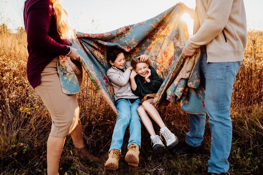 Boy and girl swinging on quilt during family photos