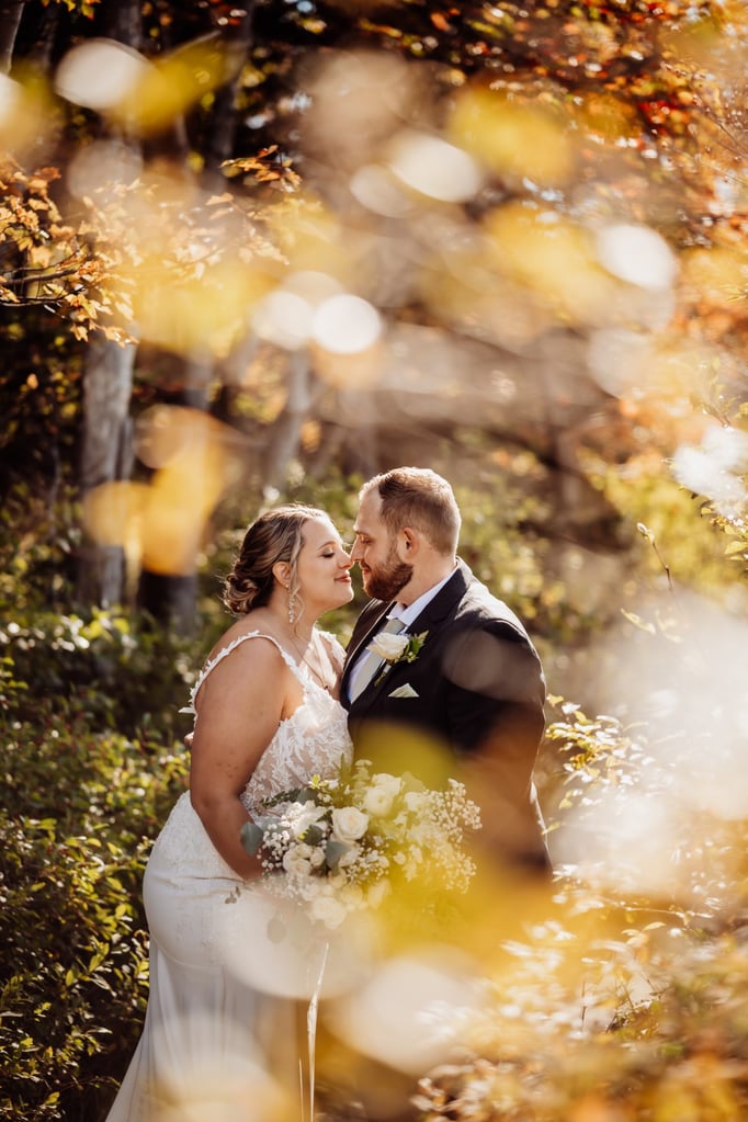 Intimate Acadia National Park wedding portrait of the couple surrounded by fall leaves and soft golden sunlight.