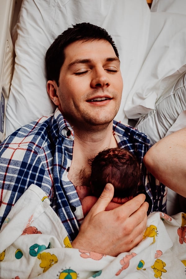 Father holding newborn baby on his chest for the first time after birth