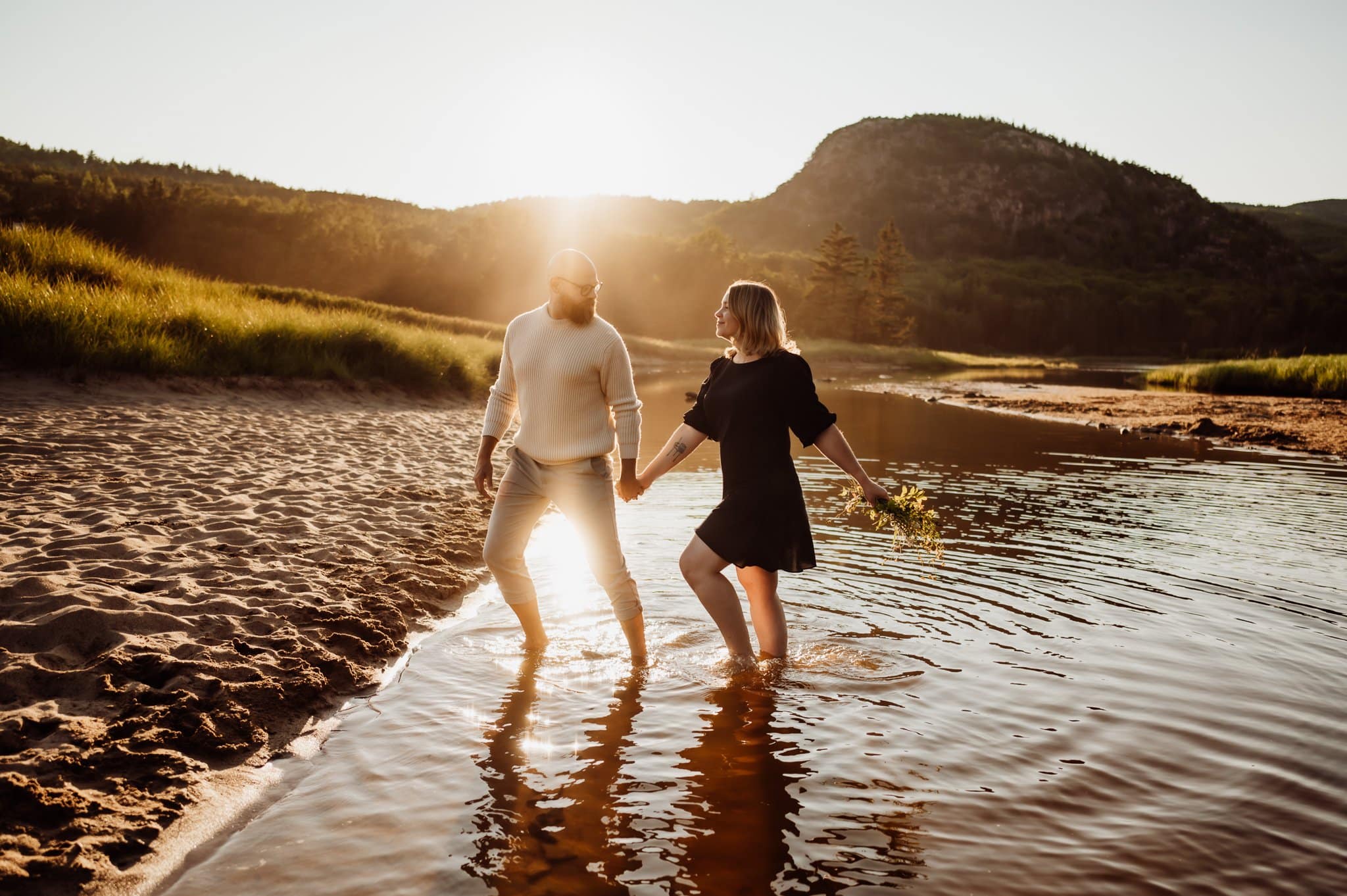 Couple walking in water holding hands in Acadia national park