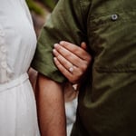Womans hand wrapped around fiance arm showing engagement ring