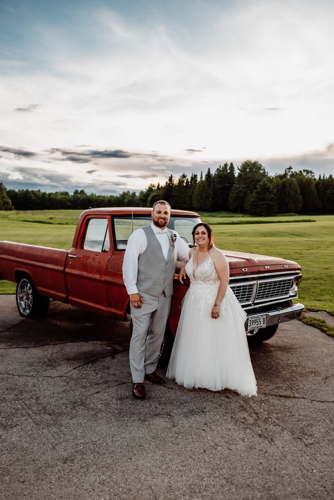 bride and groom posing in front of antique red truck at sunset meadows in corinna maine