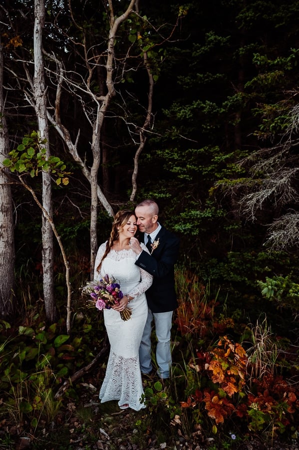 Groom pinching brides chin in front of trees and woods