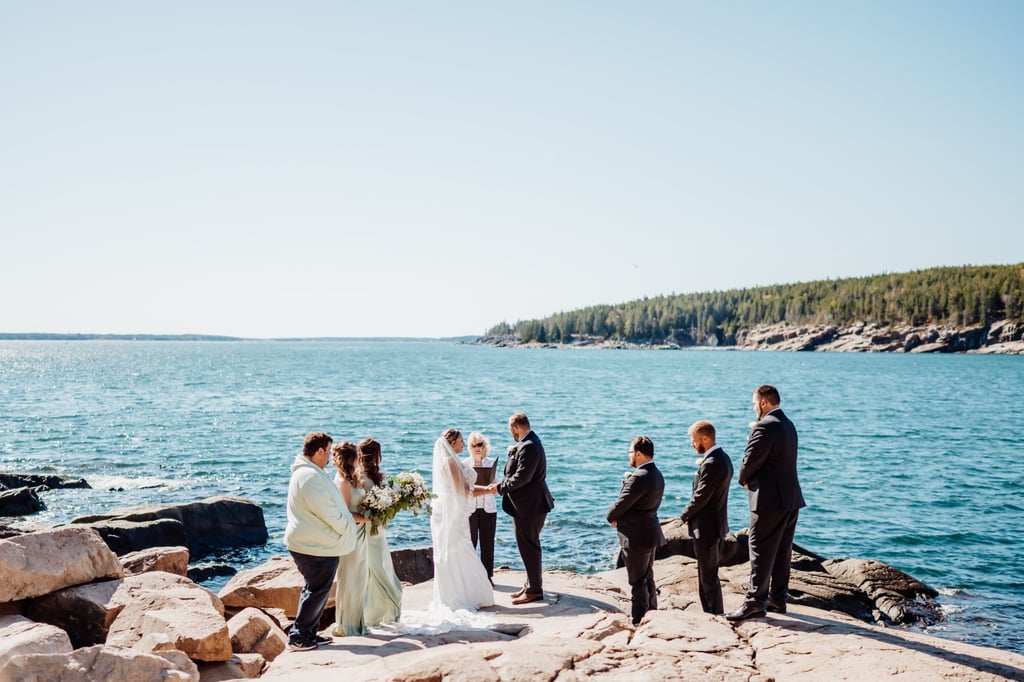 Wedding ceremony on the cliffs of Acadia National Park, with the couple exchanging vows before the vast blue ocean and evergreen coastline near Bar Harbor, Maine.